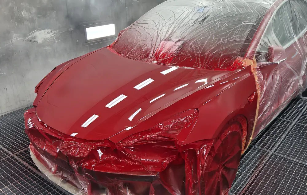 Homme en train de peindre une carrosserie de voiture