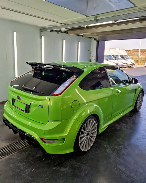 Peintre en train de peindre une voiture de sport en orange